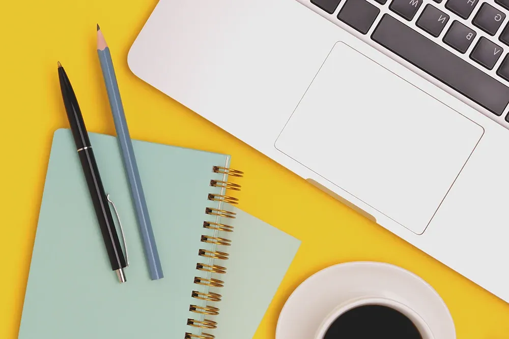 A laptop next to a small notebook with a pen and pencil. Used to represent other types of testing at 美高梅mgm集团.